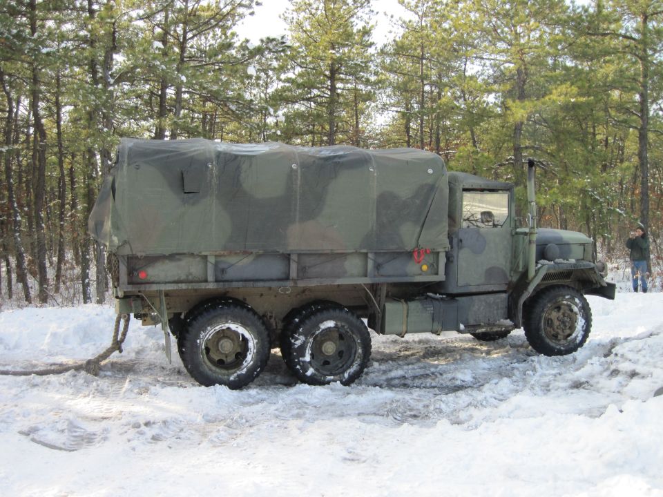 Side view of a camouflaged military truck in the snow