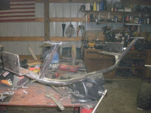 1995 Ford Bronco - A shop-built bare-steel tube bumper with welded mounting plates and upright light tabs sits clamped in a bench vise, still unpainted with g…