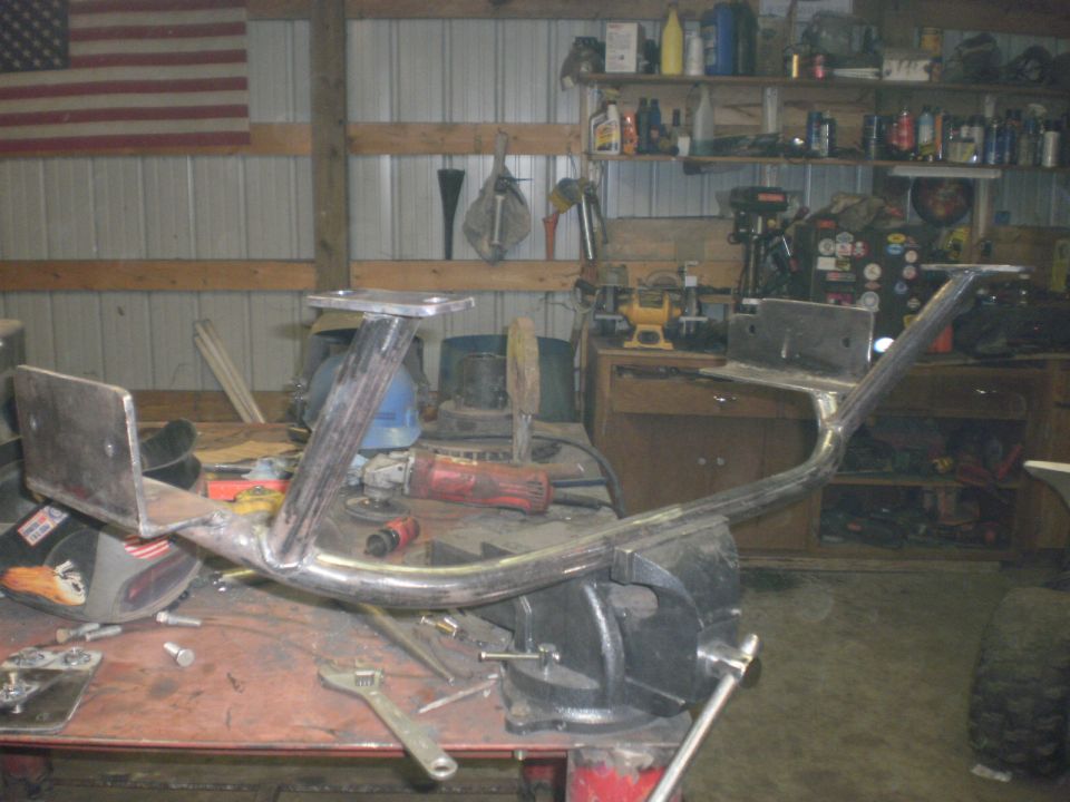 Home-fabricated bare steel tube bumper clamped in a vise on a shop bench