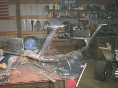 1995 Ford Bronco - A bare-steel tube bumper in progress clamped in a bench vise, showing welded upright light-mount stanchions with flat top plates and bolt-o…