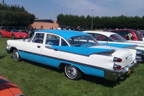 1991 Ford LTD Crown Victoria - A turquoise-and-white 1959 Dodge four-door sedan with tall swept tailfins sits on grass at an outdoor car show, seen from the rear three-qu…