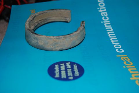 1982 Ford Bronco - A metal bearing part rests on a blue document that contains text and a Supermotors logo.