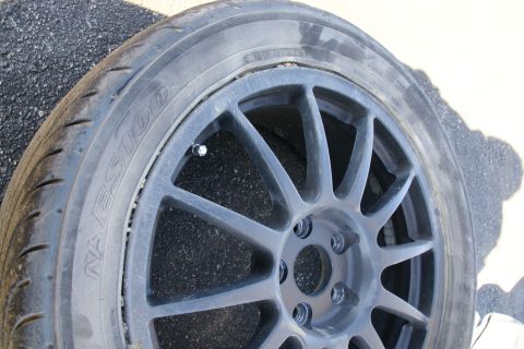 1995 Ford Taurus - A close-up view of a dark gray aftermarket wheel and a worn tire with visible text.