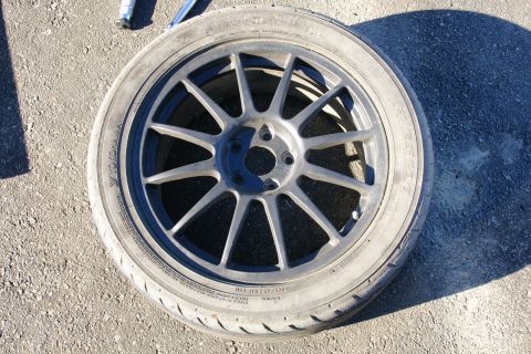 1995 Ford Taurus - Aftermarket wheel and tire assembly resting on asphalt, with tire sidewall markings visible.