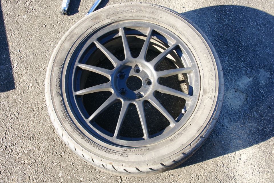 Close-up of a dark gray multi-spoke aftermarket wheel with a Yokohama tire mounted on asphalt