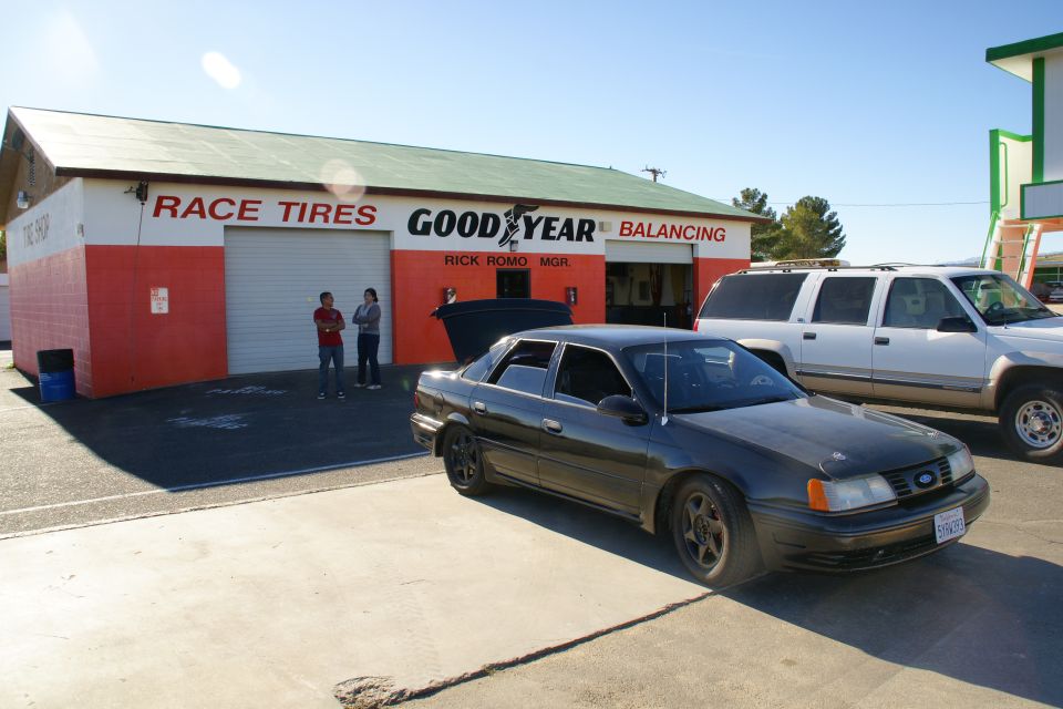 dark sedan and white SUV parked in front of a Goodyear tire shop