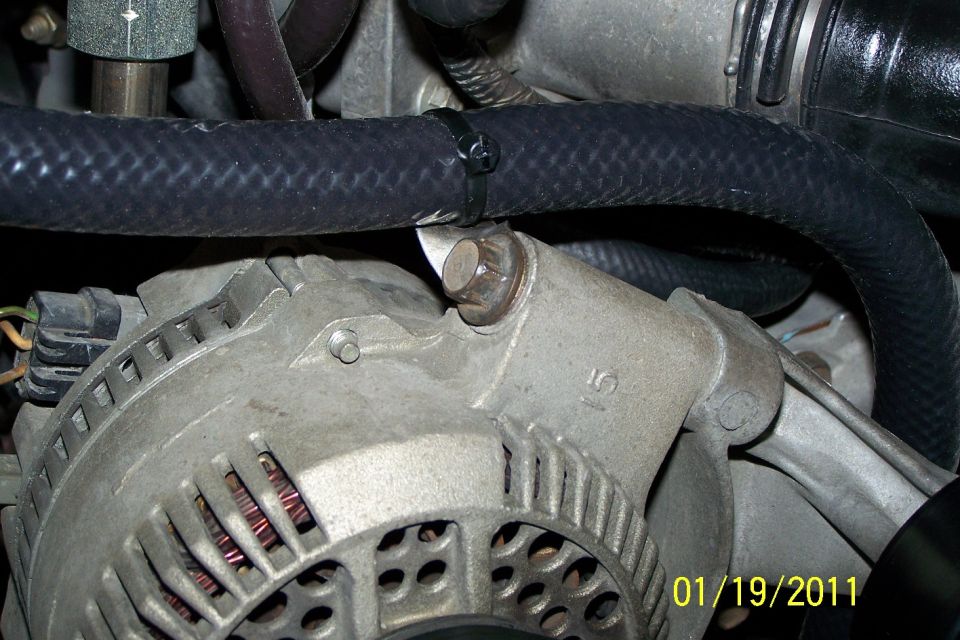 Close-up of engine bay alternator with copper windings and black hoses above