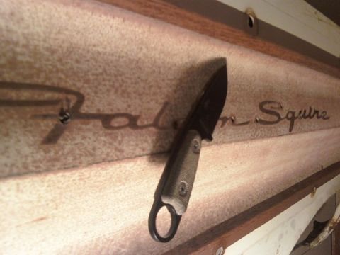 1984 Ford Bronco - A knife rests on a wooden panel with the embossed text 'Falcon Squire'.