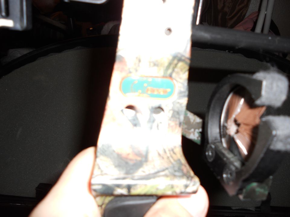 Hand holding camouflage compound bow with a teal and yellow logo