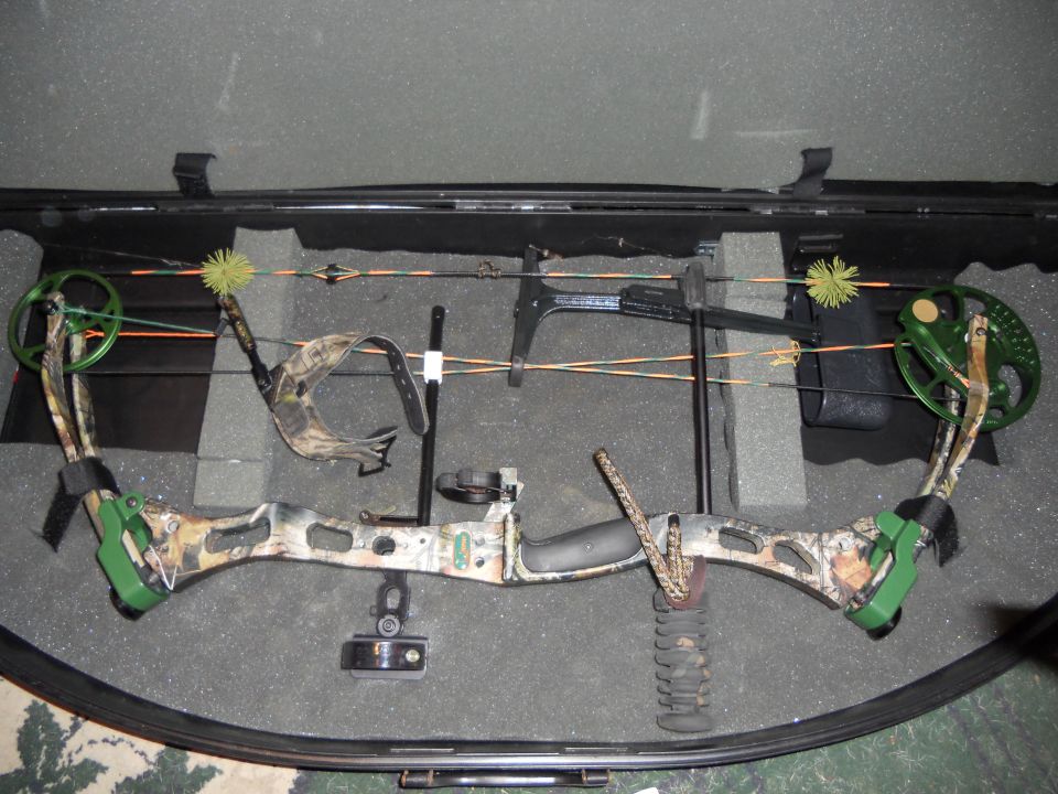 Compound bow with green accents and camouflage pattern in a black case