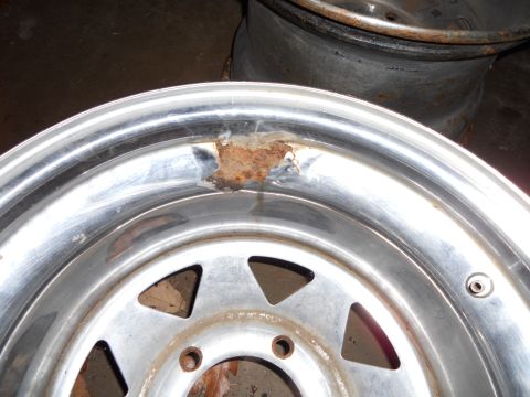 1992 Jeep Cherokee - A close-up of a damaged chrome wheel, showing rust and wear.