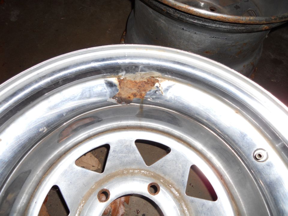 Chrome wheel with rust damage on the lip and triangular cutouts