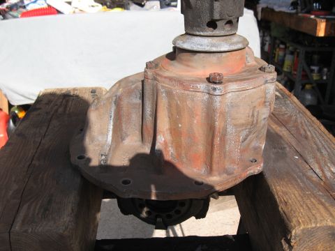 1968 Shelby GT500 - A close-up view of a rusty differential housing, resting on wooden beams.