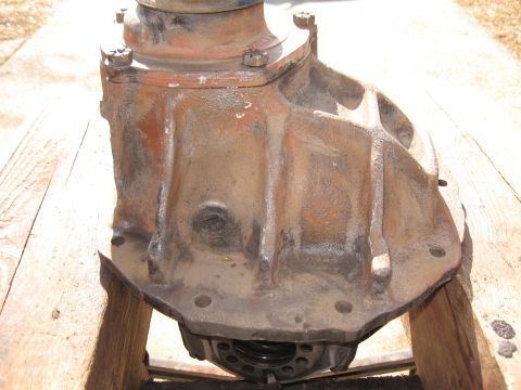 1968 Shelby GT500 - A rusty differential housing is shown mounted on wooden supports, with visible bolts and a circular flange at the bottom.