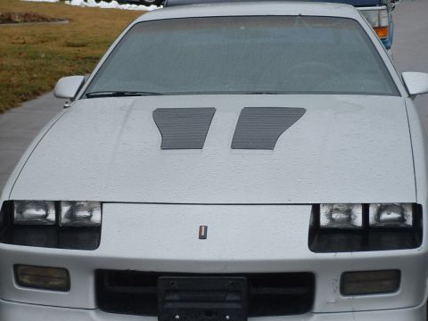 1985 Chevrolet Camaro - A silver 1985 Chevrolet Camaro is parked outside on a wet day.