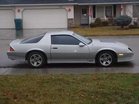 1985 Chevrolet Camaro - A silver Chevrolet Camaro from the early 1980s is parked on a suburban street.