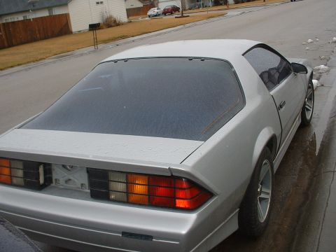 1985 Chevrolet Camaro - Rear view of a silver 1985 Chevrolet Camaro coupe parked on a wet street.