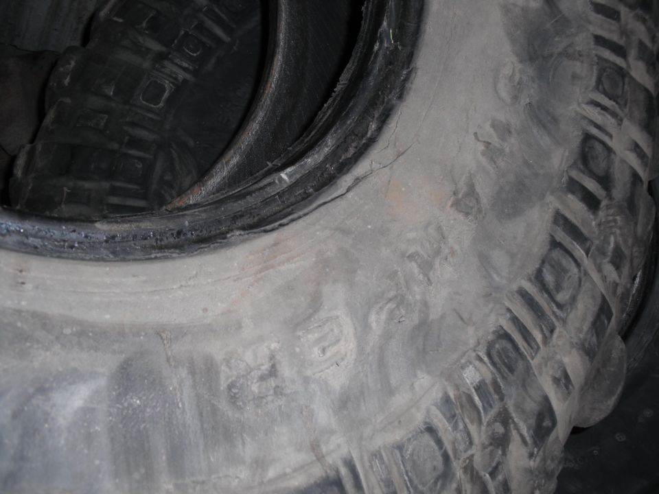 Close-up of a dusty off-road tire sidewall and blocky shoulder tread lugs