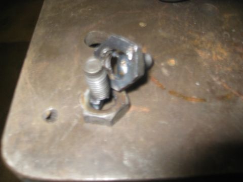 1994 Jeep YJ - A close-up view of a metal bracket secured by a bolt and nut on a textured surface.