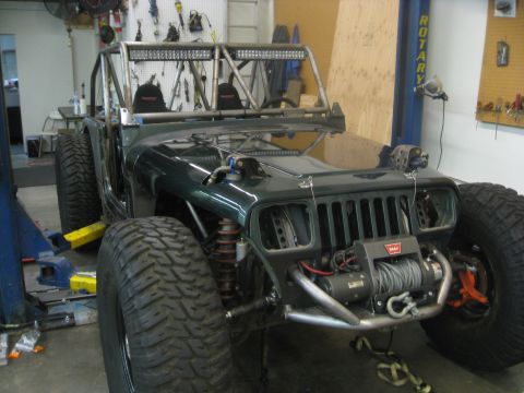1994 Jeep YJ - A modified Jeep Wrangler with a custom roll cage and off-road tires is shown in a workshop setting.