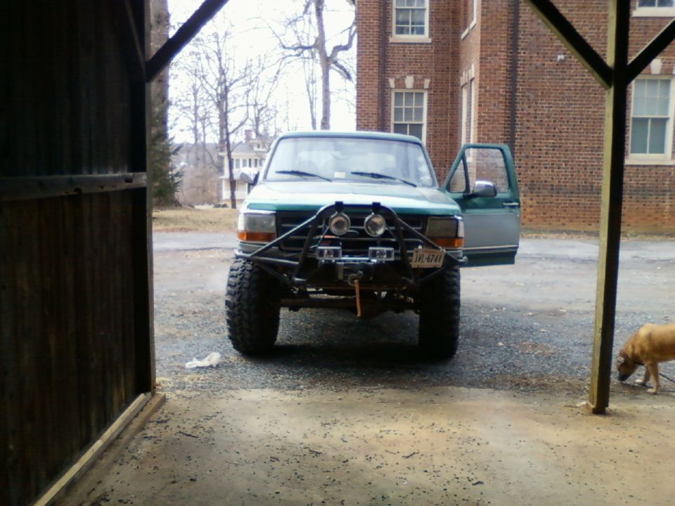 Green 1996 Ford Bronco with custom bumper and winch, front view