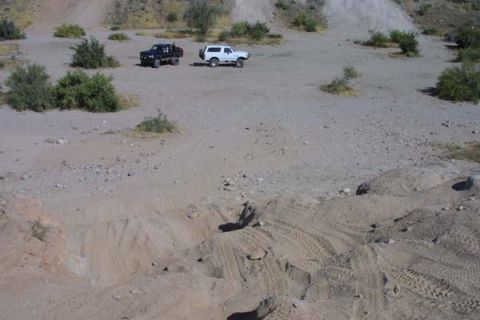 1993 Ford Bronco - Two SUVs are parked in a dry, outdoor area with tire tracks visible in the dirt.
