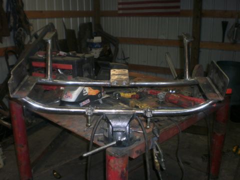 1995 Ford Bronco - A custom metal part, possibly a crossmember, is secured in a vise on a workbench with various tools visible.