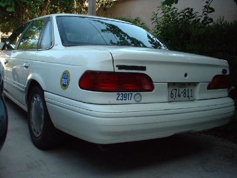 1996 Ford Taurus - This white sedan has a '311' sticker and a license plate that reads 674-811.