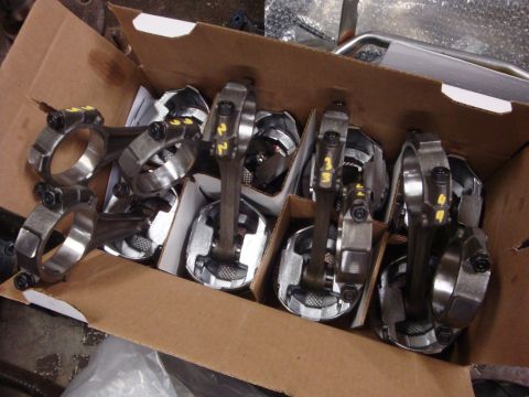 1989 Ford Bronco - A box contains several pistons and connecting rods, some with yellow numbering, likely for an engine rebuild.