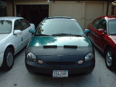 1996 Ford Taurus - A green 1996 Ford Taurus is parked in front of a garage, flanked by two other sedans.