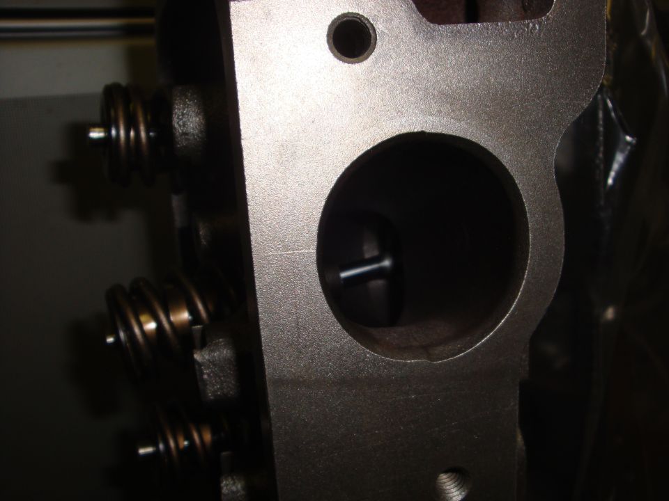 Close-up into a cylinder head intake port showing the valve back and installed valve springs