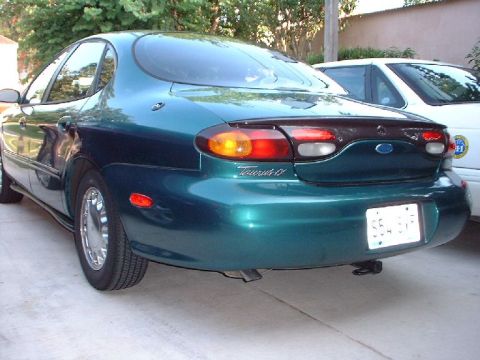 1996 Ford Taurus - Rear view of a 1996 Ford Taurus sedan, showing its taillights and a portion of another vehicle.