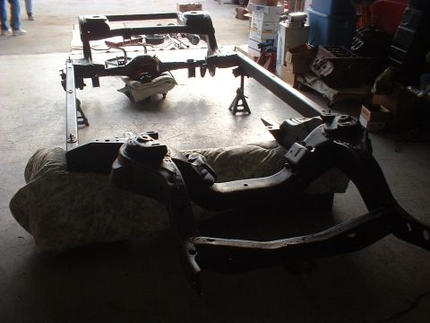 1967 Ford Galaxie - Vehicle frame and suspension parts are laid out on the floor, possibly for restoration or repair.