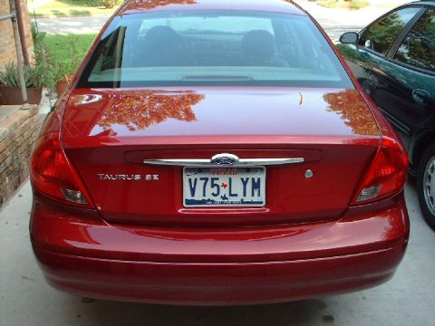 1996 Ford Taurus - The rear of a red 1996 Ford Taurus SE is shown, parked next to another vehicle.