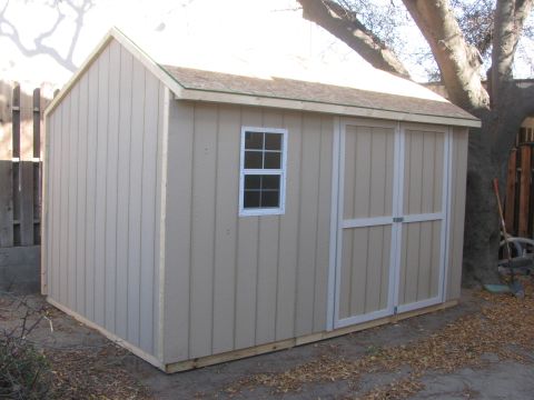 1968 Ford Mustang - A tan shed with a window and double doors sits in a yard with fallen leaves.