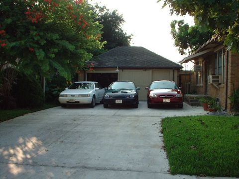 1996 Ford Taurus - Three sedans are parked in a driveway in front of a residential garage.