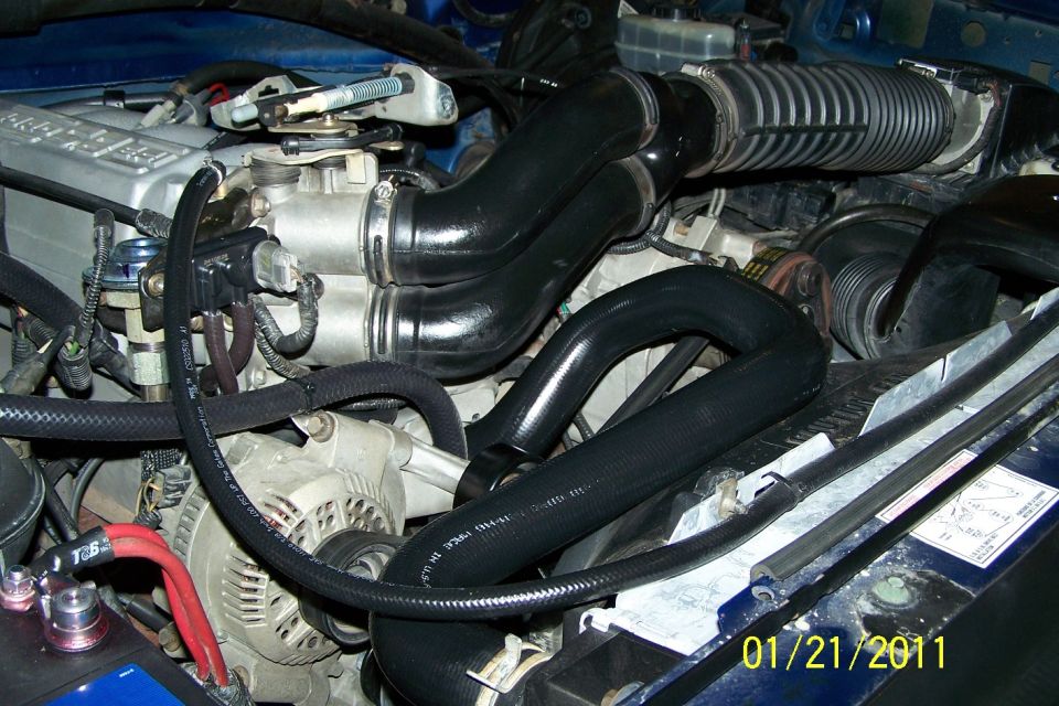 Engine bay with black intake hoses, silver alternator and throttle body