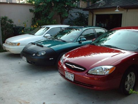 1996 Ford Taurus - Three Ford Taurus sedans are parked in a driveway, two of which are visible from the front.