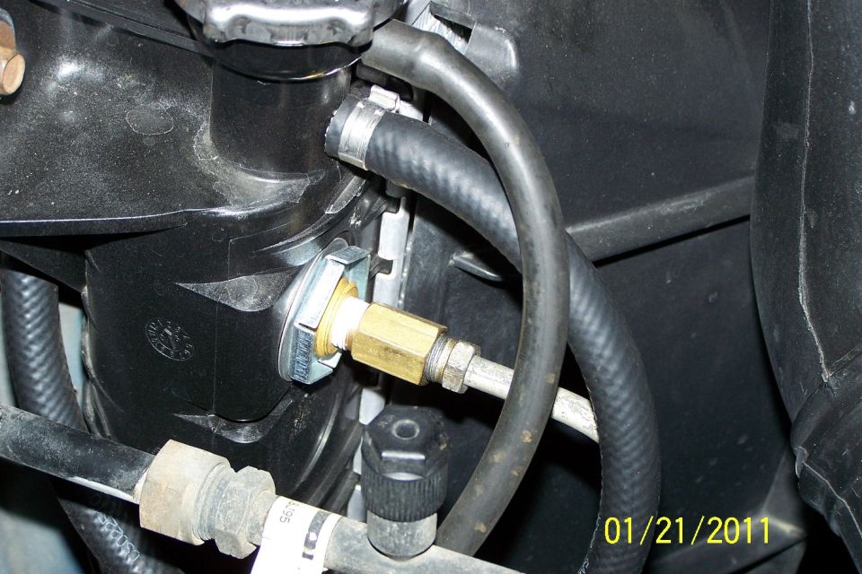 Brass compression fitting on metal line with rubber hoses in engine bay