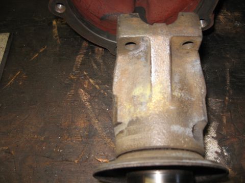 1968 Shelby GT500 - Close-up of a metal automotive part, likely from a differential, against a stained workbench.