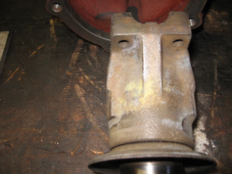 Cast iron differential housing part with yellow and white residue, on a dark wooden surface