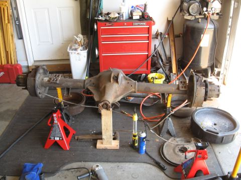 1995 Ford F-150 - A disassembled rear axle assembly is supported by jack stands in a garage setting.