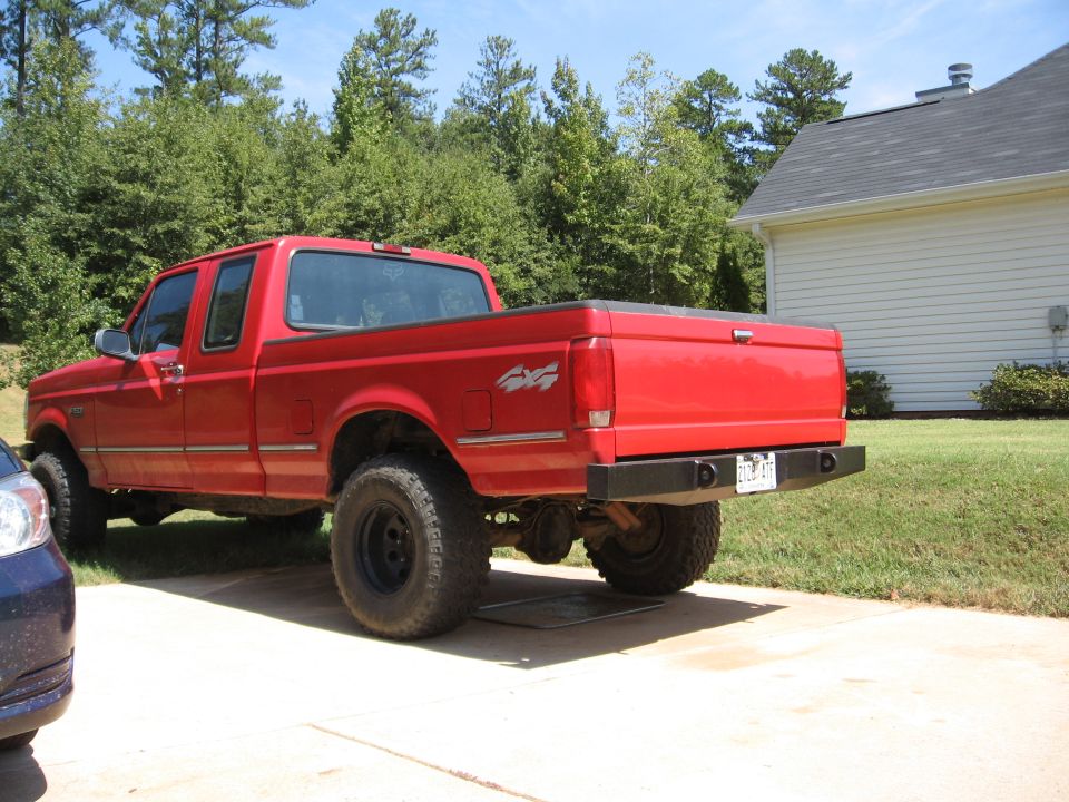 Red Ford F-150 extended cab 4x4 pickup rear three-quarter view on a driveway
