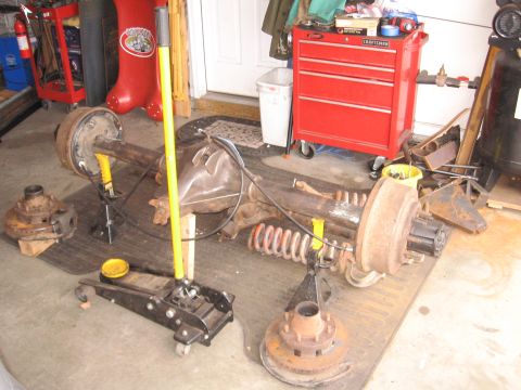 1995 Ford F-150 - A disassembled truck rear axle assembly is laid out on the floor with tools and equipment nearby.