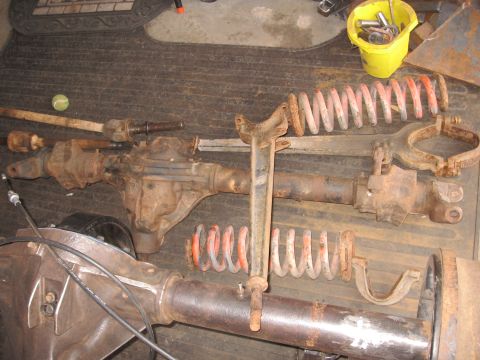1995 Ford F-150 - Various rusty vehicle axle components and suspension springs are displayed on a dark, textured surface.