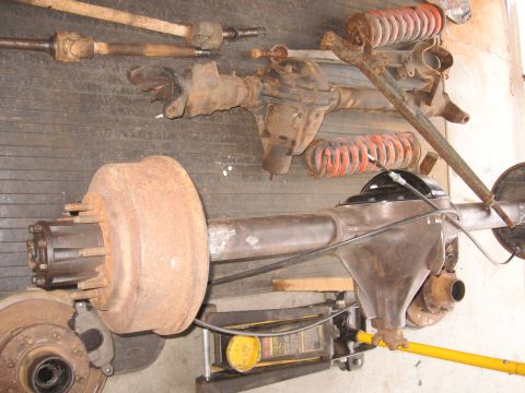 1995 Ford F-150 - Various automotive axles and suspension components are laid out, likely for repair or modification.