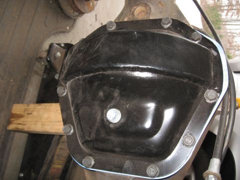 1995 Ford F-150 - Close-up of a black rear differential cover bolted to a solid axle housing, with a visible weld seam across the face, a zinc-plated fill pl…