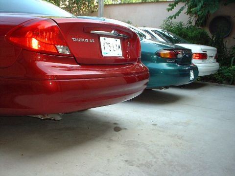 1996 Ford Taurus - Three sedans are parked in a row, with the rear of a red 1996 Ford Taurus SE in the foreground.