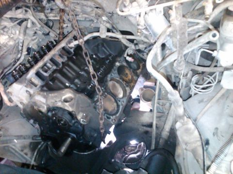 1989 Ford Bronco - Engine block assembly with valves and lifters visible, being worked on with a chain hoist.