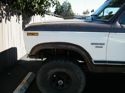 1982 Ford Bronco - A two-tone Ford Bronco is seen from the front quarter panel, parked outdoors.